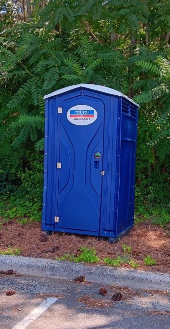 a blue portable toilet in the woods