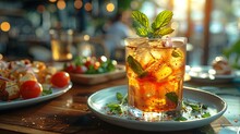 a glass of liquid with ice and mint leaves on a plate