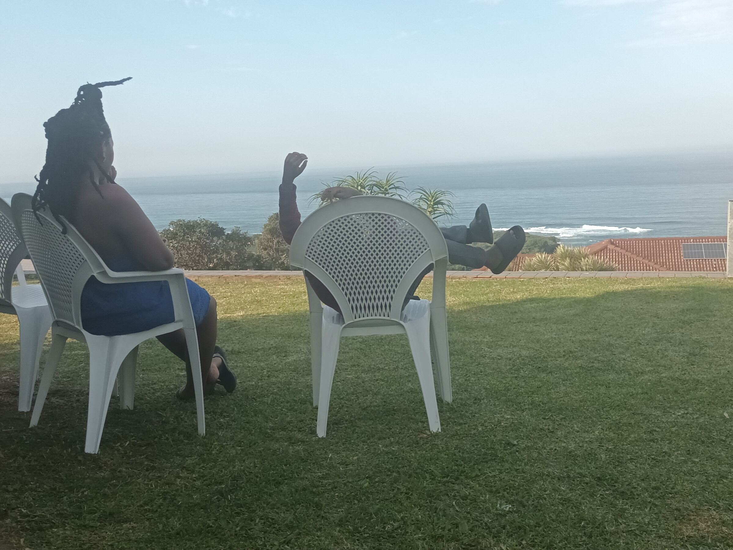 two people sitting in chairs on a lawn