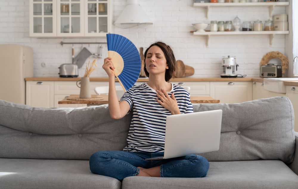 a woman sitting on a couch holding a fan