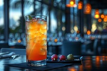 a glass of orange liquid with ice on a table