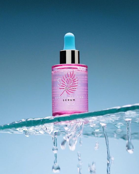 a pink bottle with a dropper on top of water