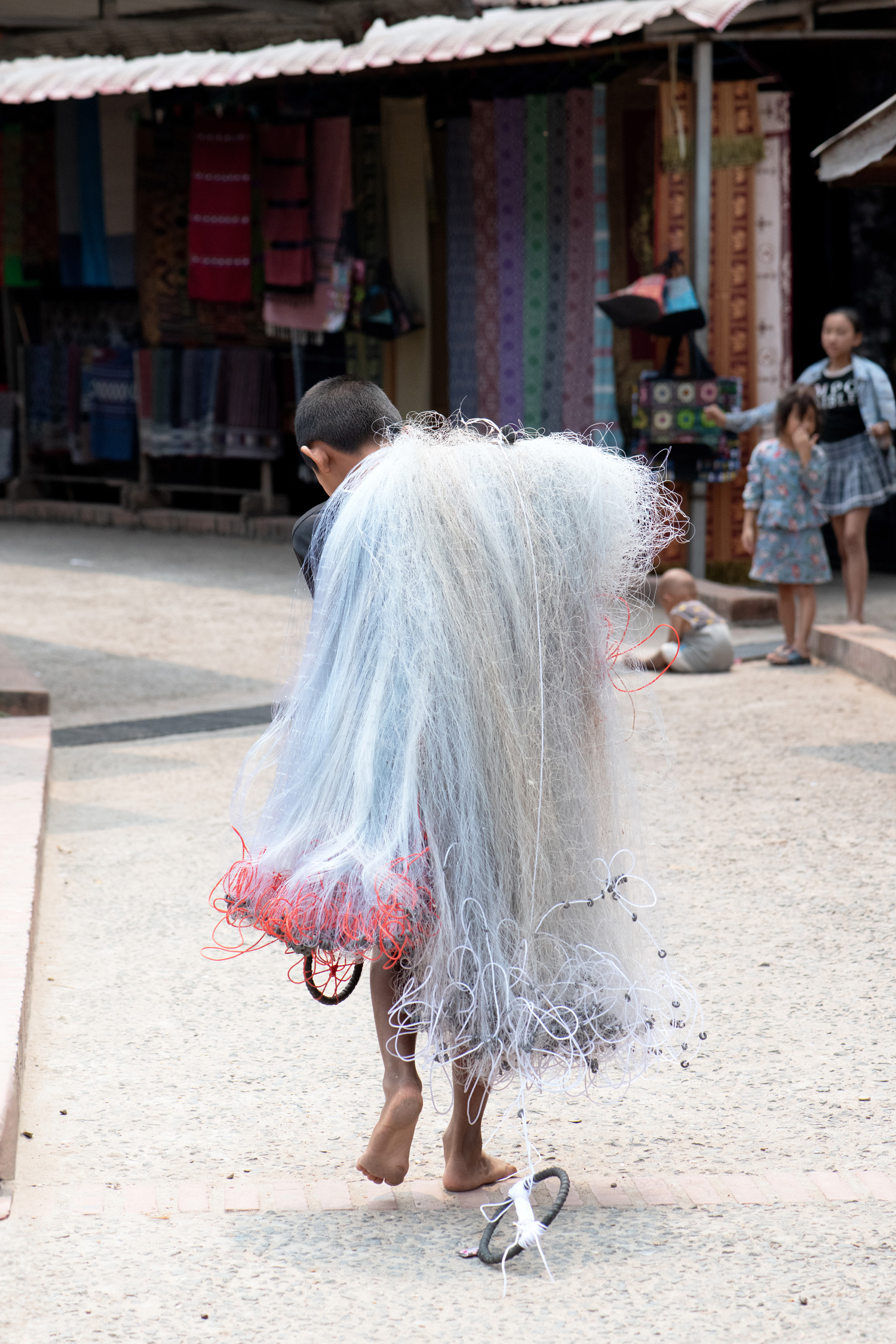 a boy walking down a street with a large net