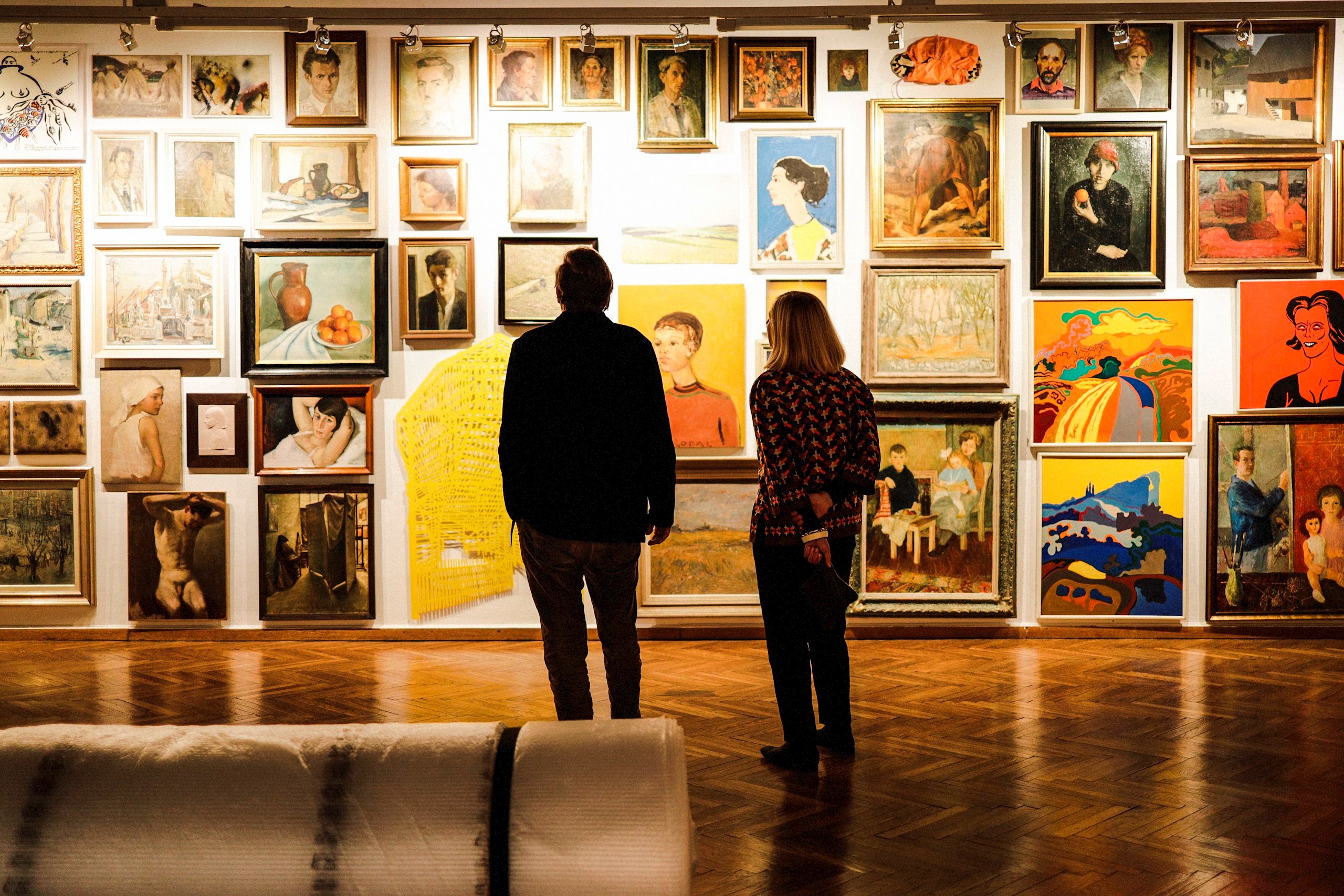 a man and woman looking at art on a wall