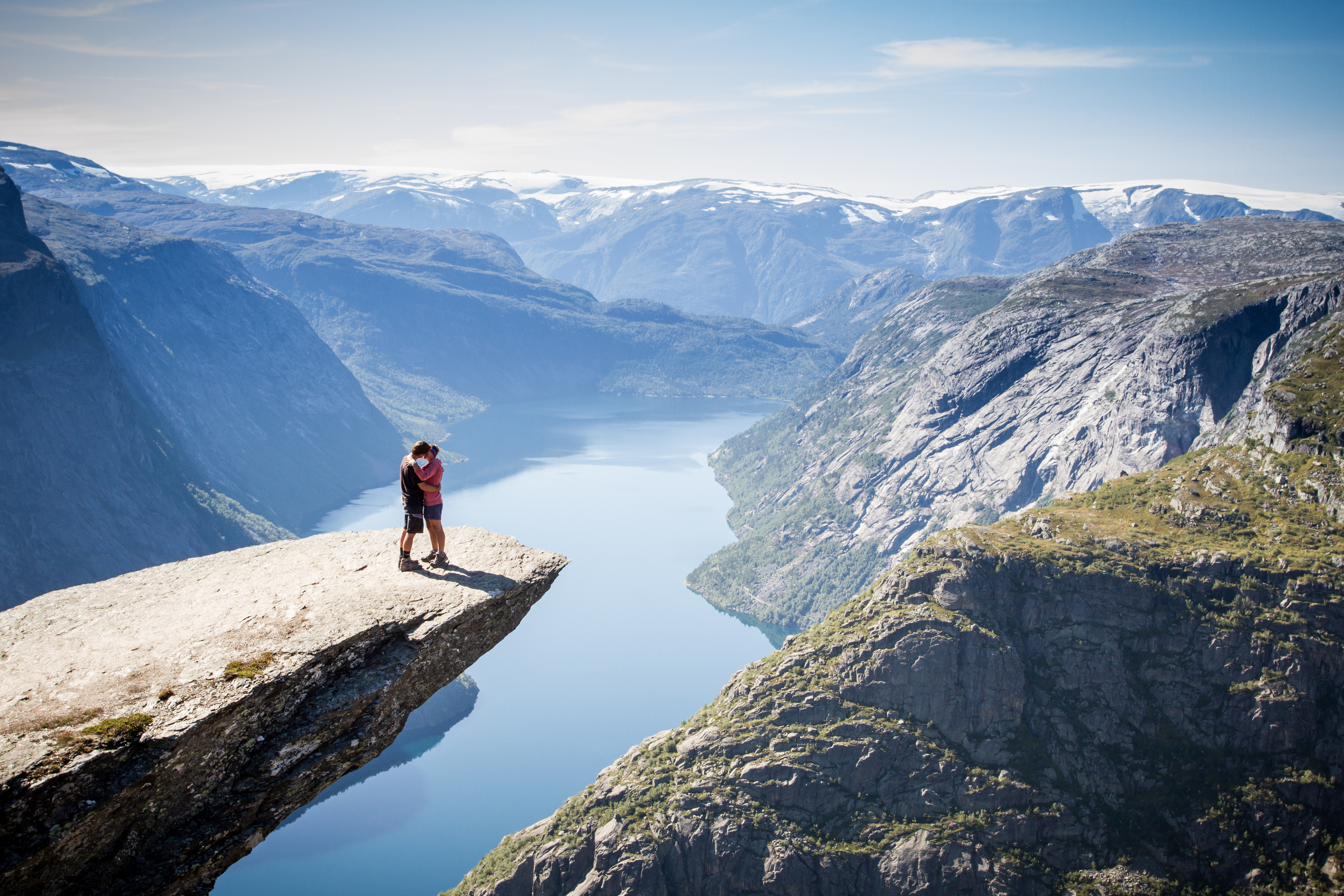 a couple of people standing on a cliff edge overlooking a river