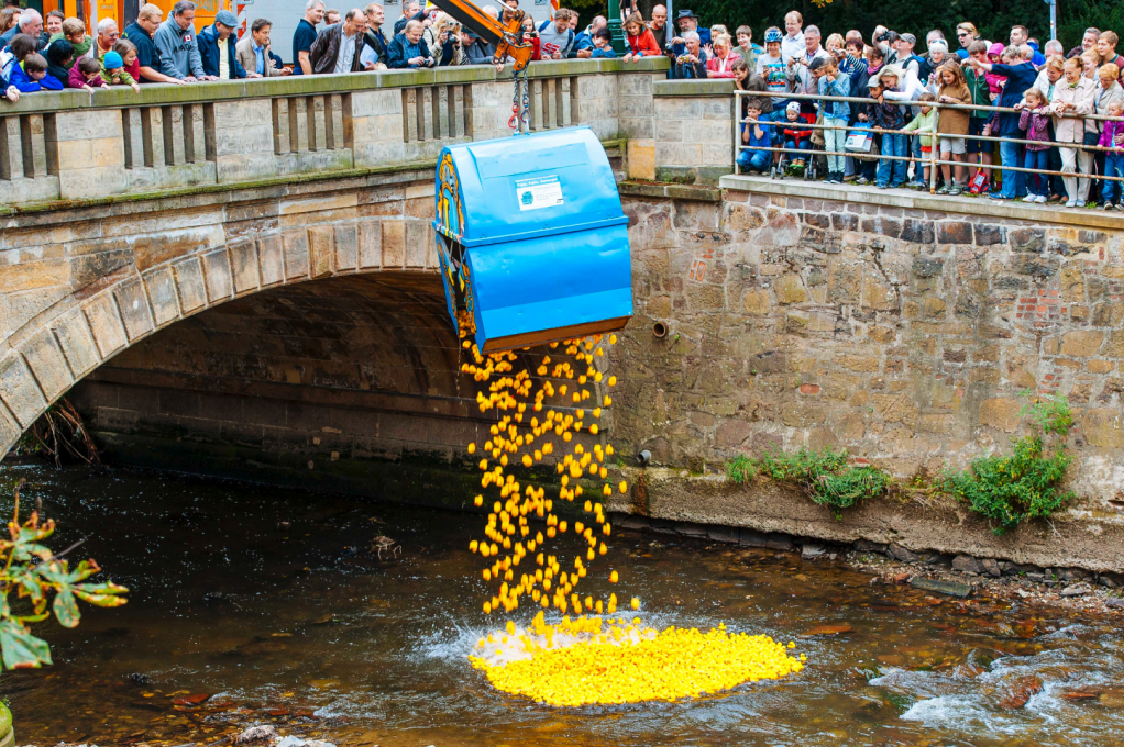 a large blue container with yellow rubber ducks falling out of it