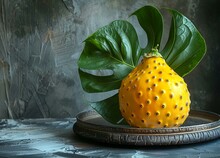 a yellow fruit with green leaves on a plate