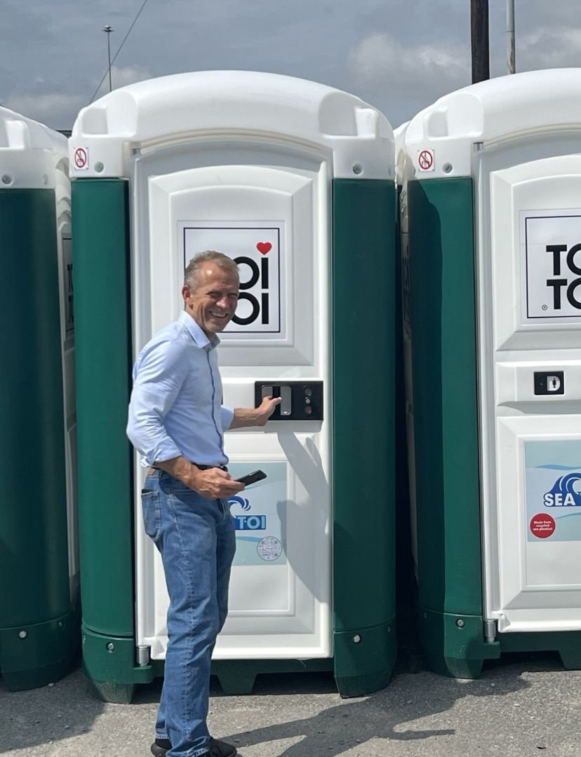 a man standing next to a row of portable toilets