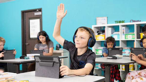 a boy raising his hand in a classroom