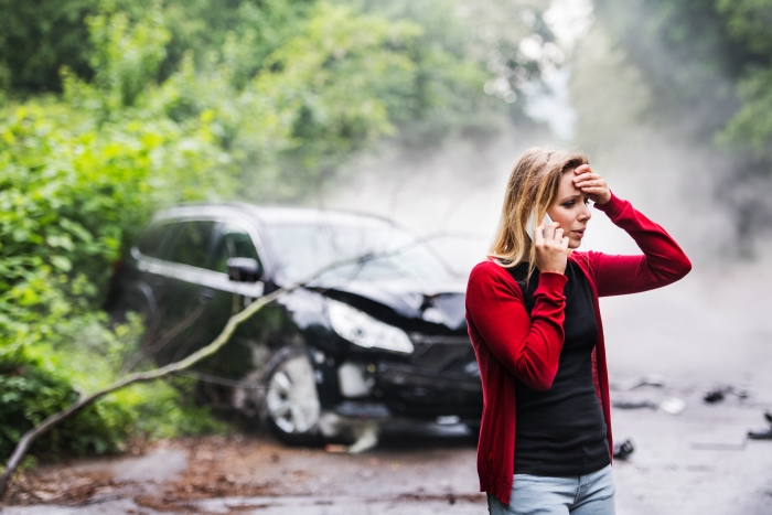 a woman talking on a phone near a car