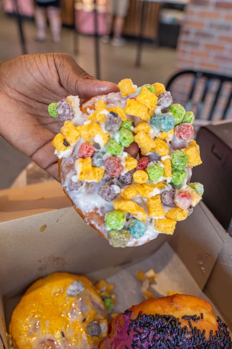 a hand holding a doughnut with cereal