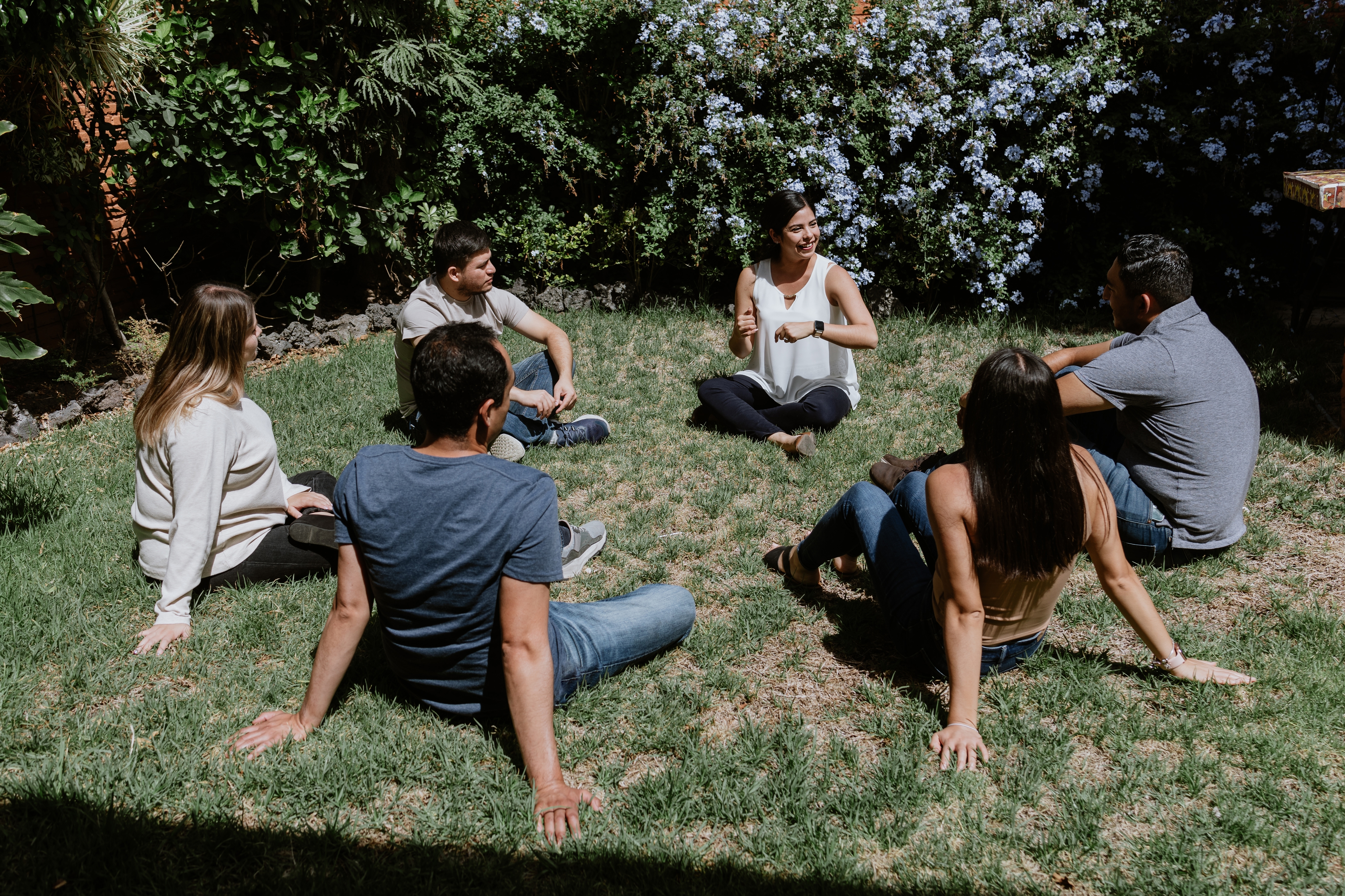 a group of people sitting in a circle on grass