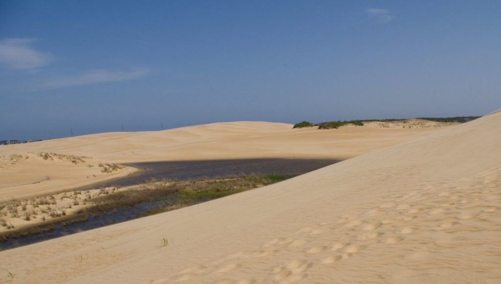 a sand dune with water in the distance