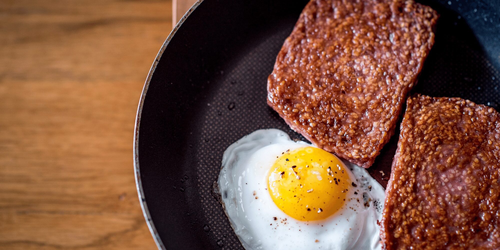 a fried egg and meat in a pan