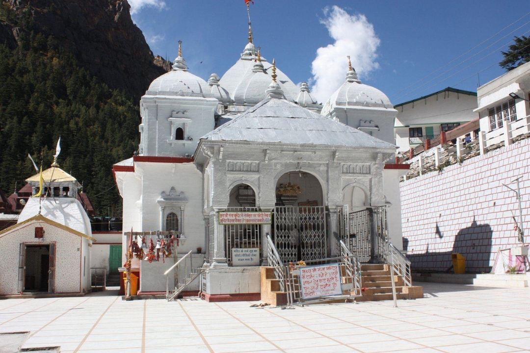 a white building with a gate and a mountain in the background