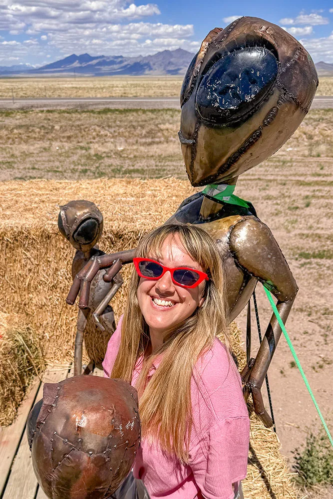 a woman posing with a statue of an alien