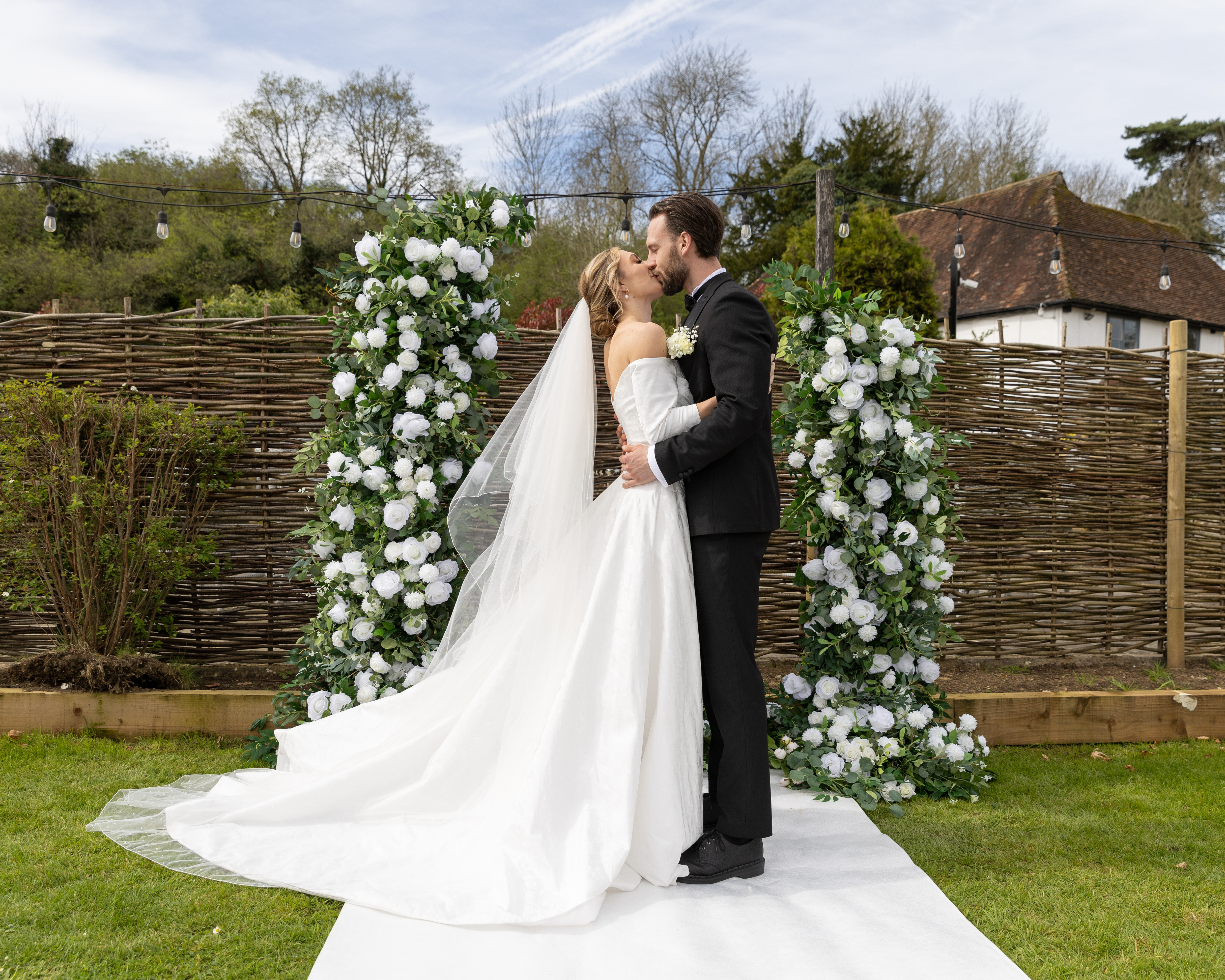 a man and woman kissing in front of a flower arch