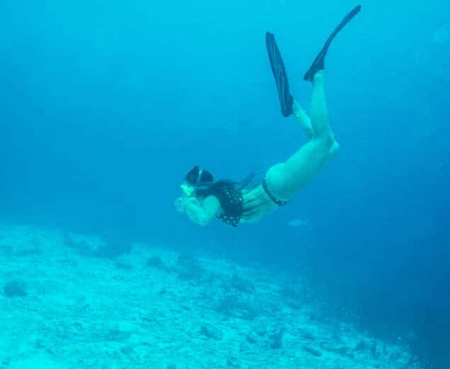 a woman swimming underwater with fins and mask