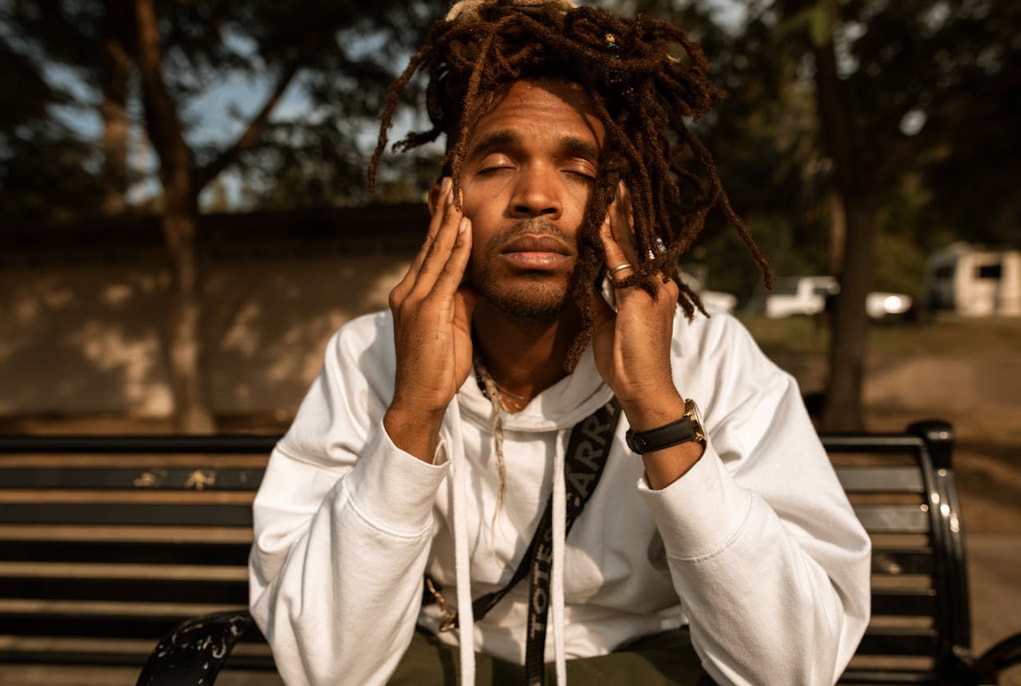 a man with dreadlocks sitting on a bench