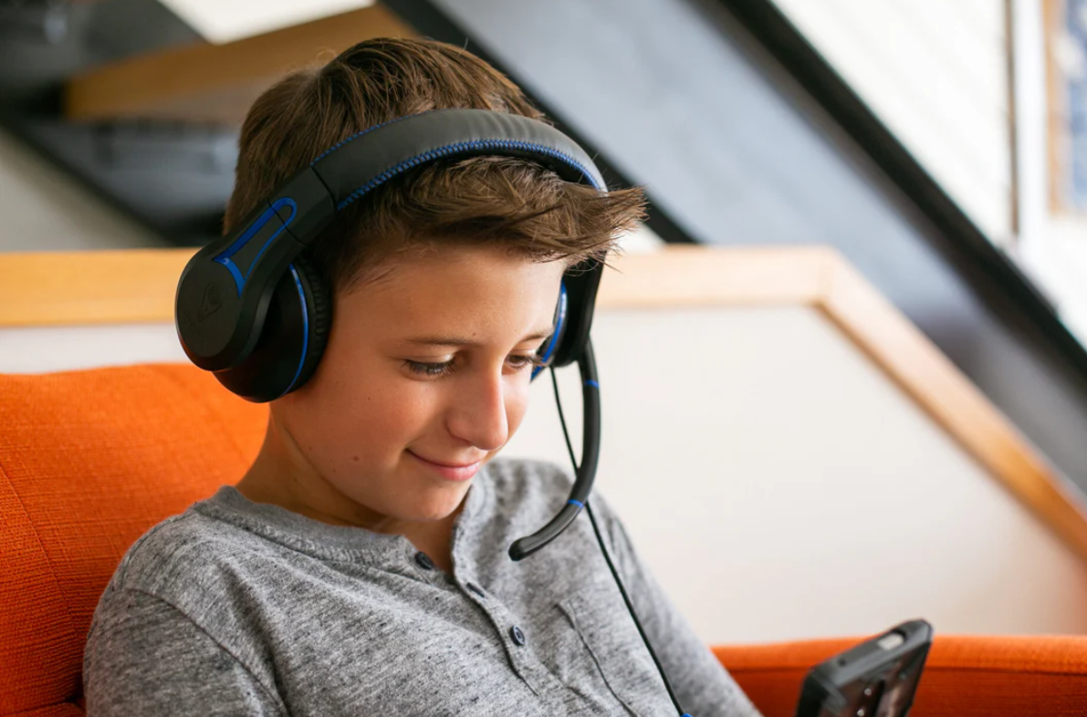 a boy wearing headphones and looking at a cellphone