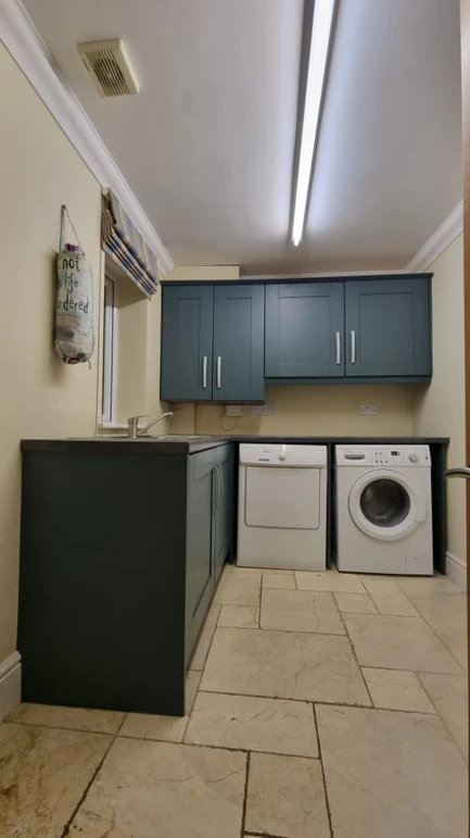 a laundry room with blue cabinets and a washing machine