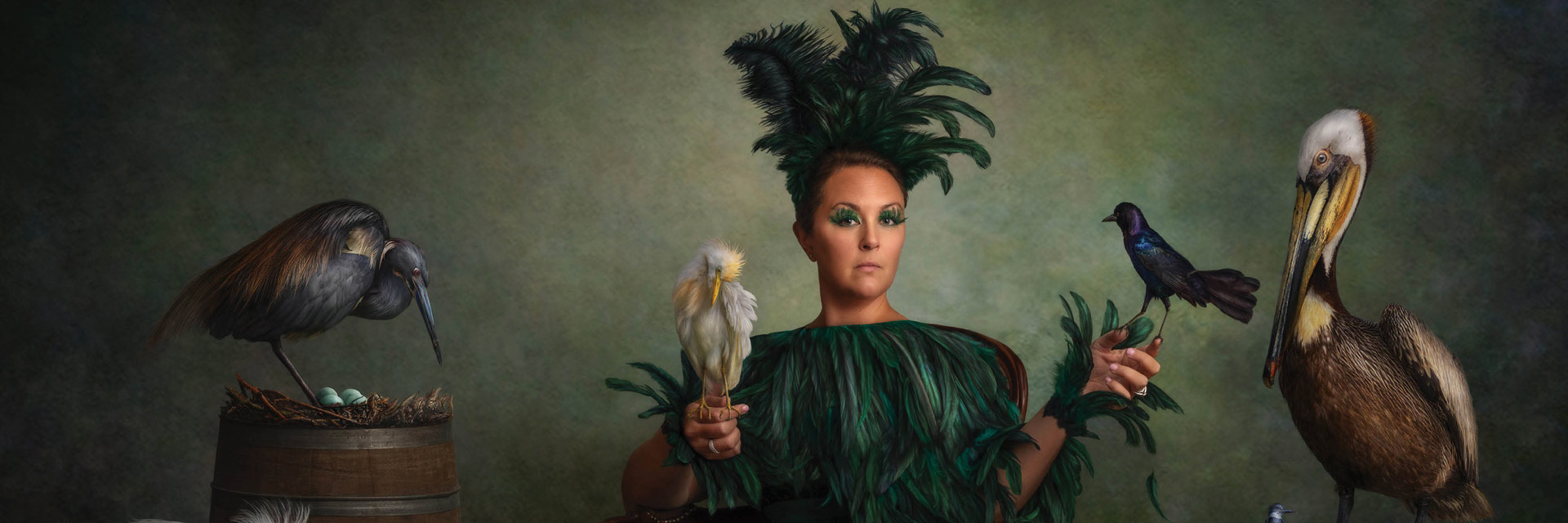 a woman in a green feathered dress holding a bird