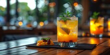 a glass of orange drink with lime and mint on a table