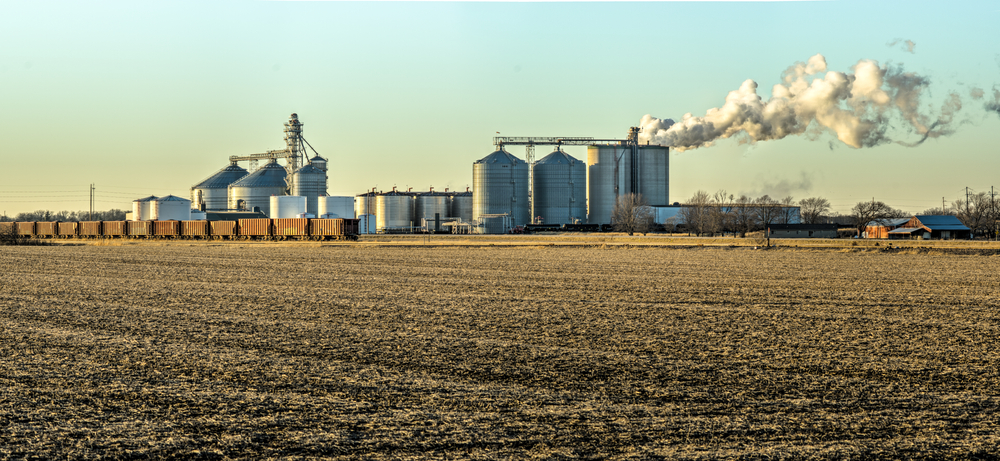 a large field with silos and smoke coming out of it