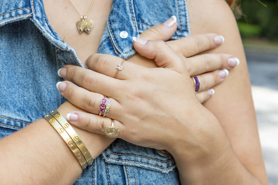 a person's hands with gold jewelry on their chest
