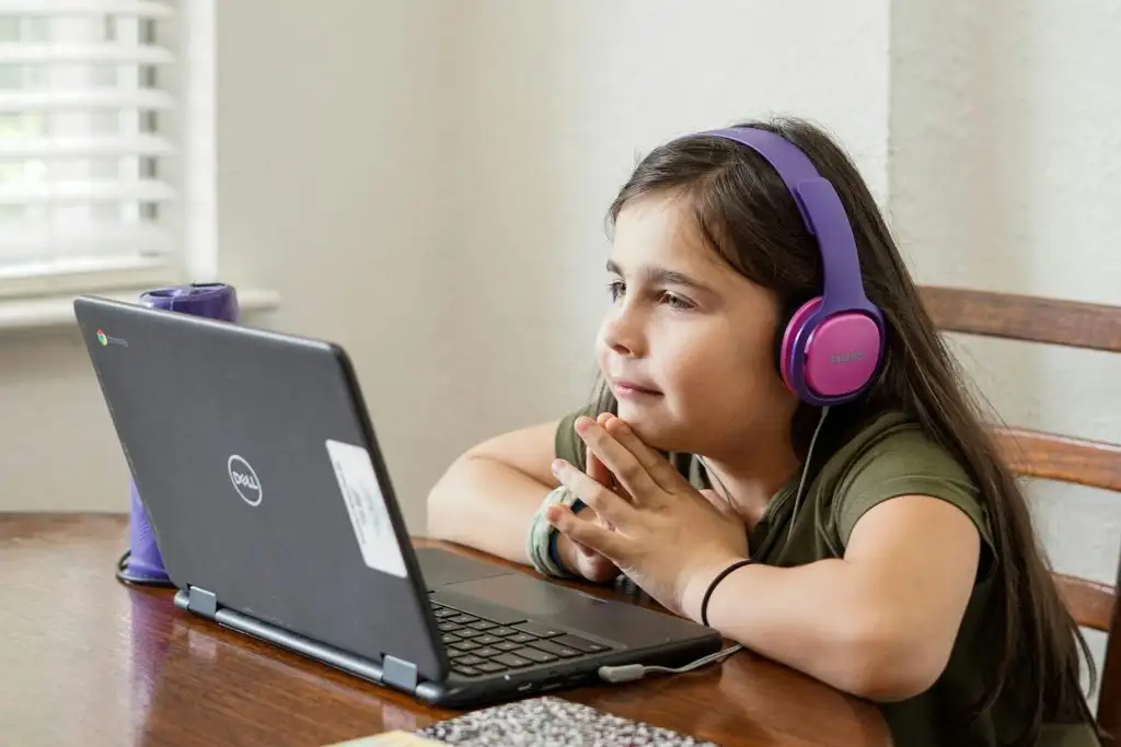 a girl wearing headphones and looking at a laptop