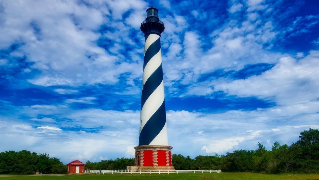 a lighthouse with a blue sky and clouds