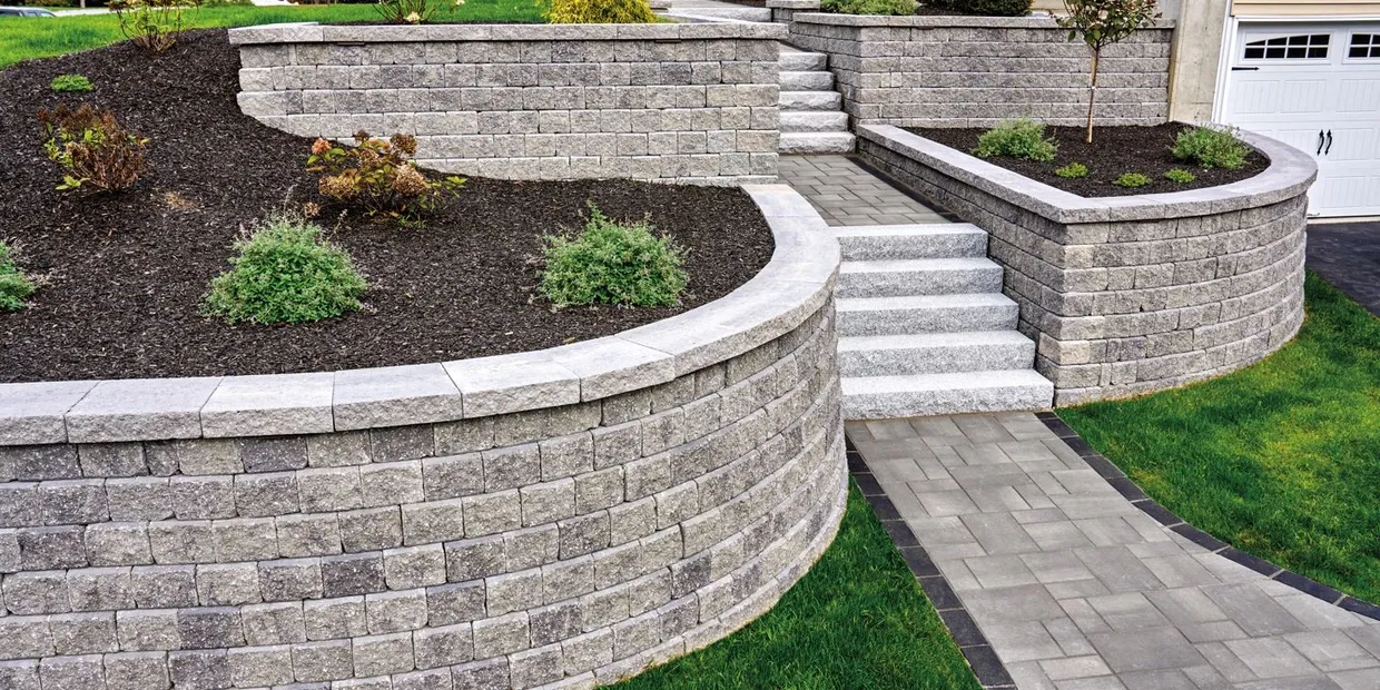 a stone retaining wall with steps and grass