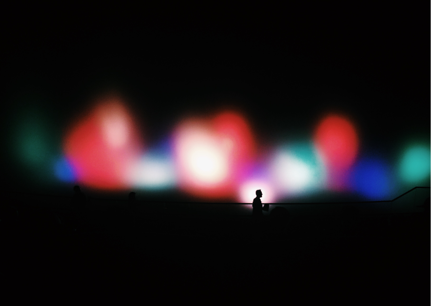 a silhouette of a person standing in front of a colorful light