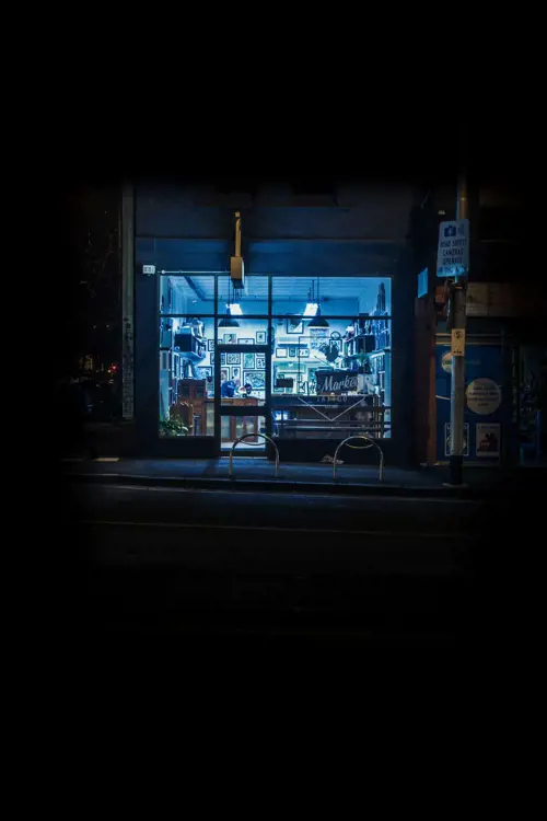 a storefront at night with a street sign