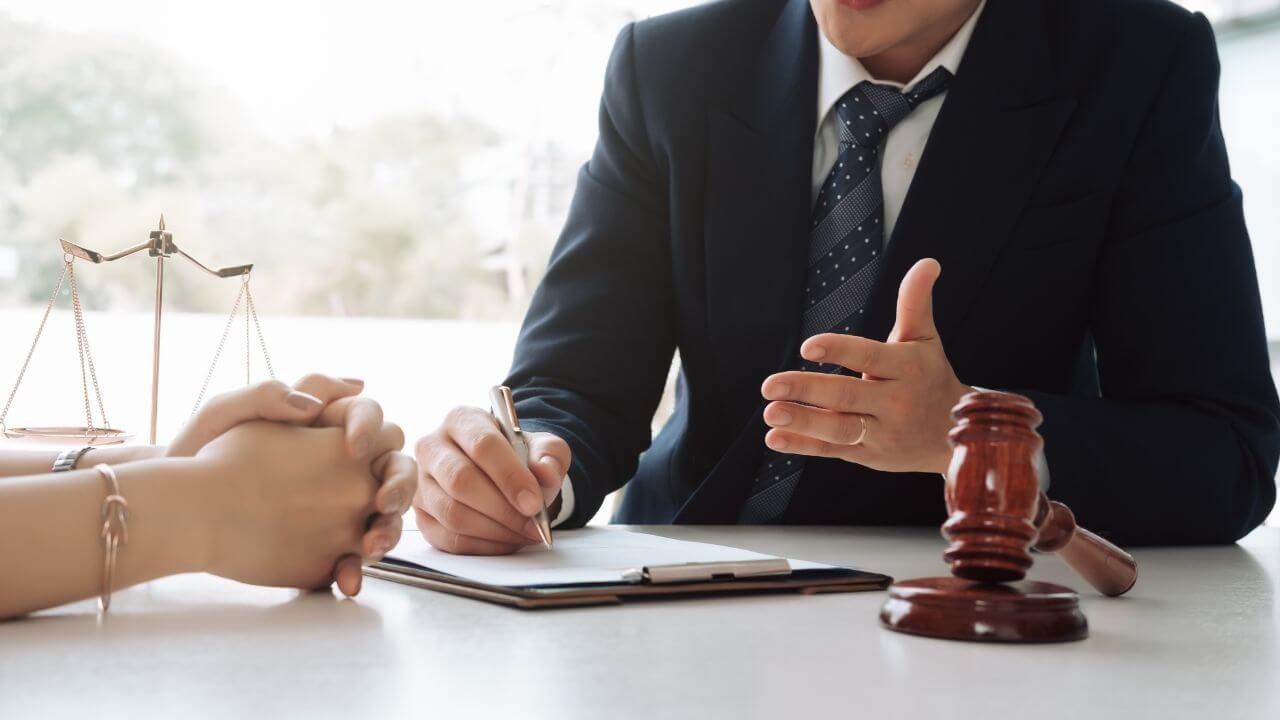 a man in a suit and tie sitting at a table with a gavel and a notepad