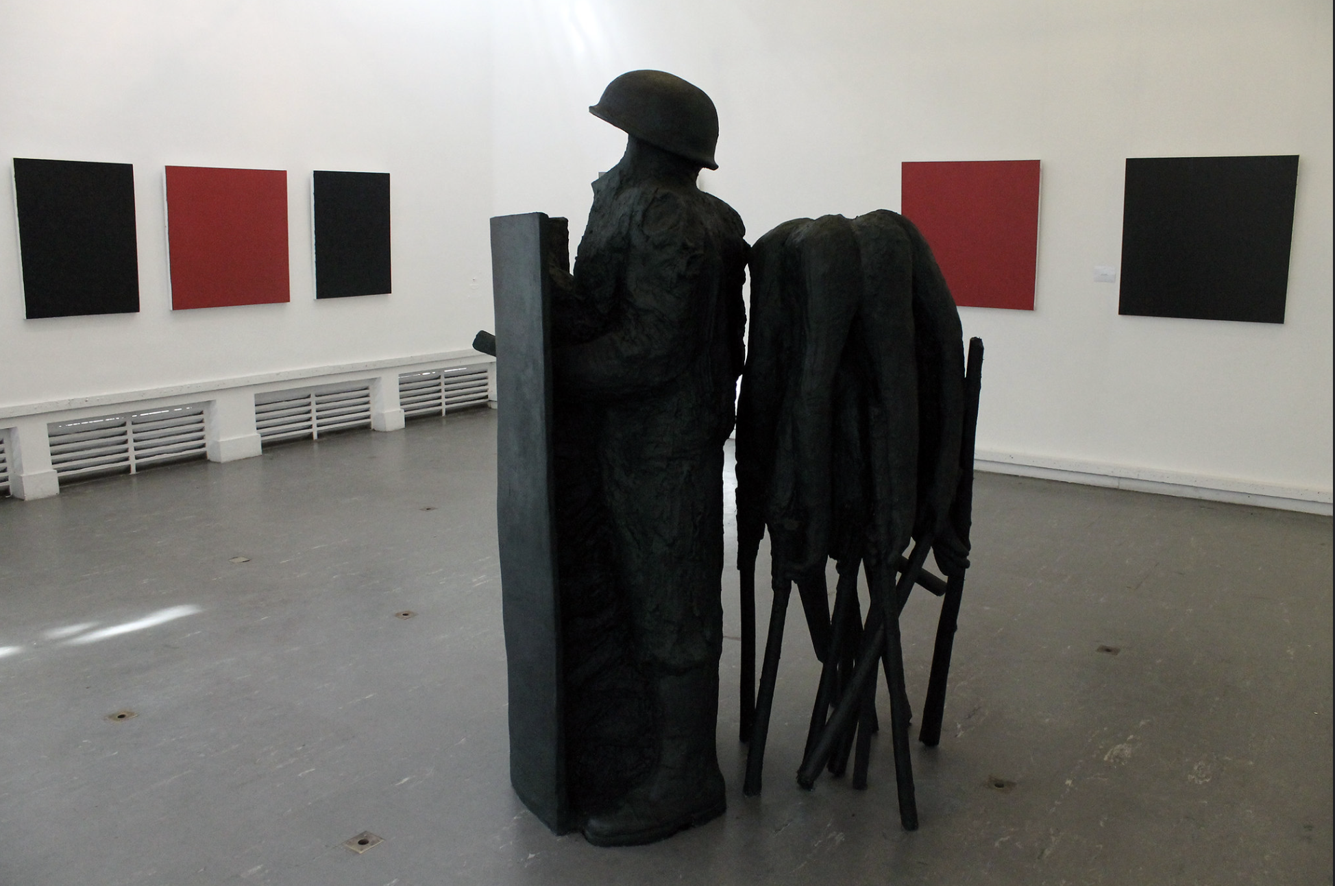 a statue of a man in a room with red and black art