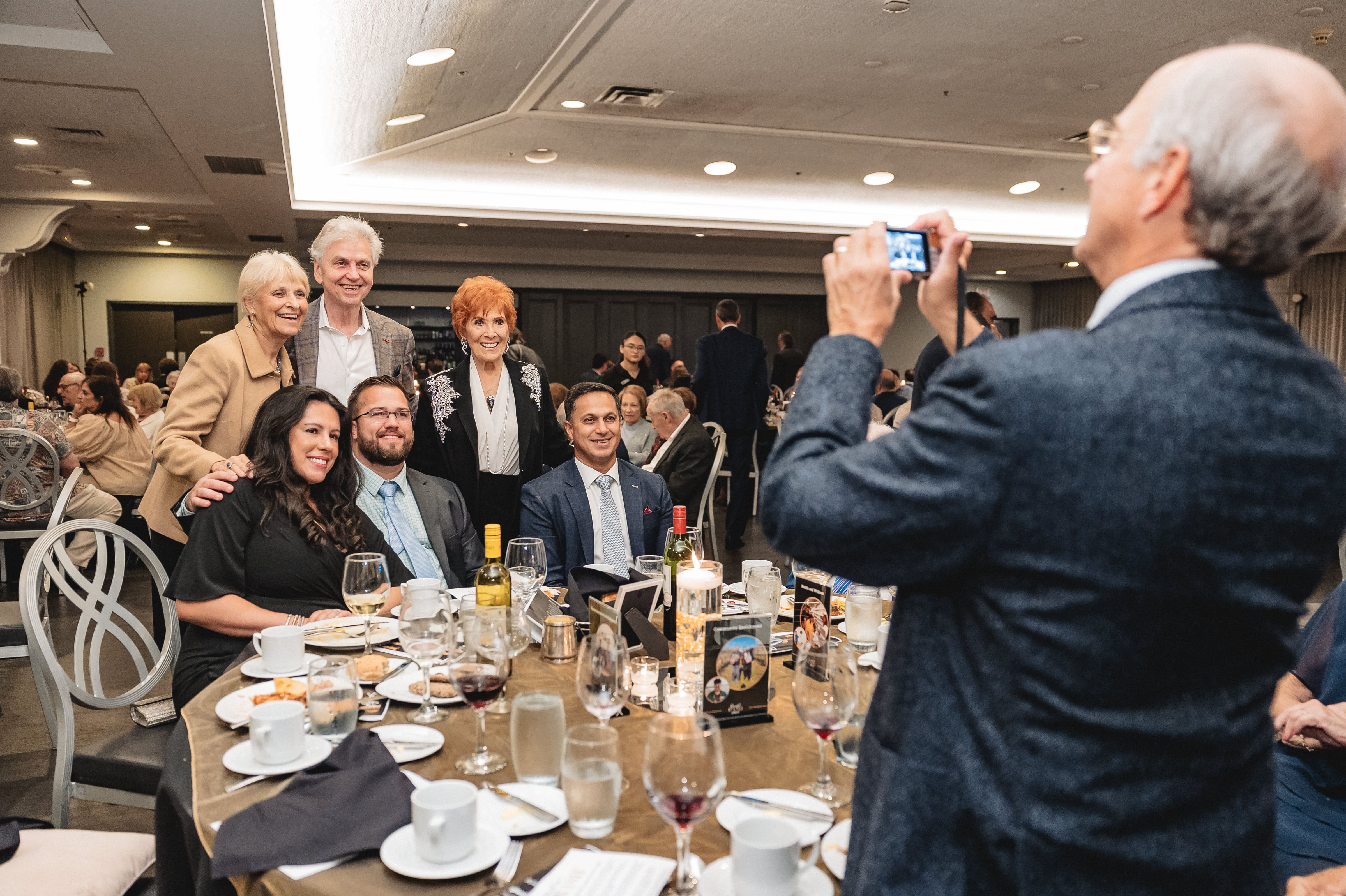 a man taking a picture of a group of people around a table
