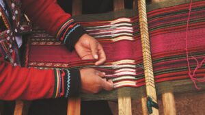 close-up of a person's hands working on a loom