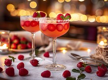 two glasses of pink drink with berries on a table