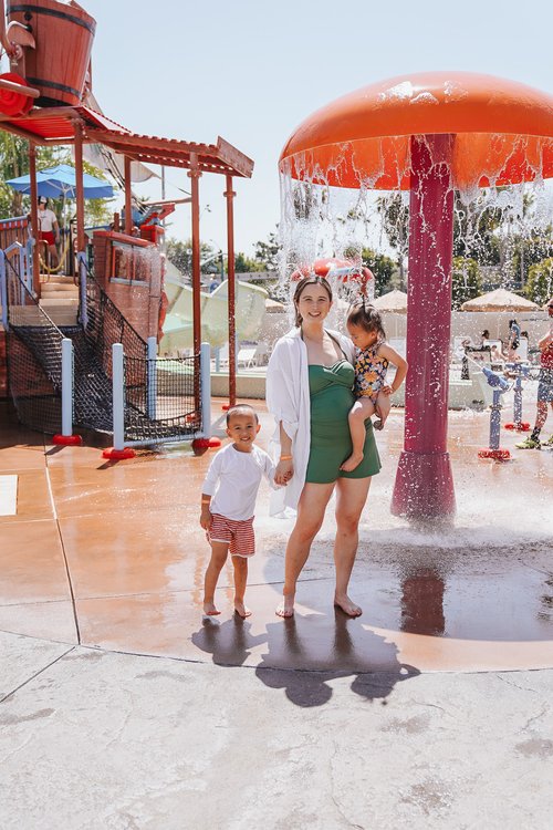 a woman holding a baby and a boy in a water park