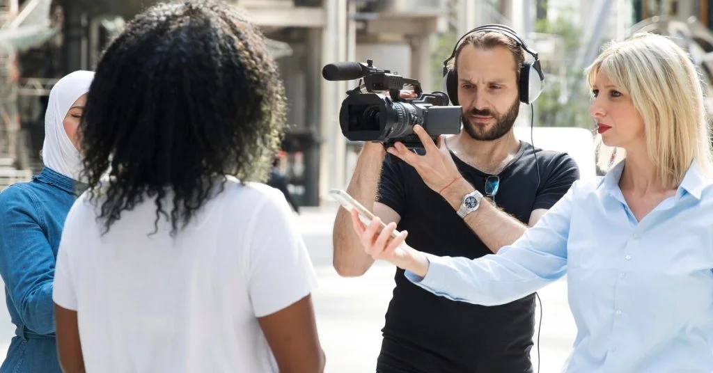 a man holding a video camera to a woman