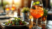 a glass of orange liquid with ice and basil leaves on a table