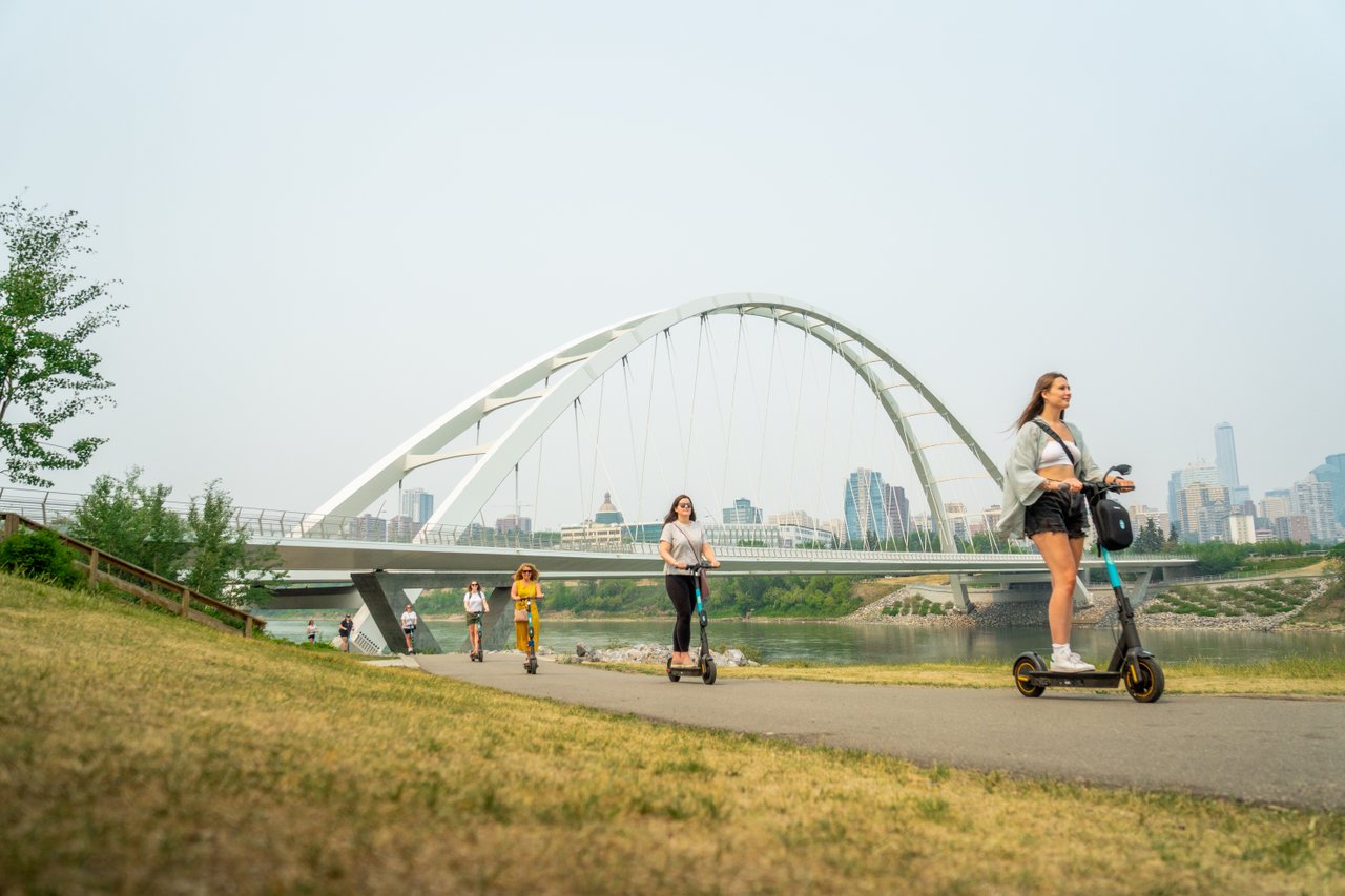 a group of people riding scooters and walking on a path