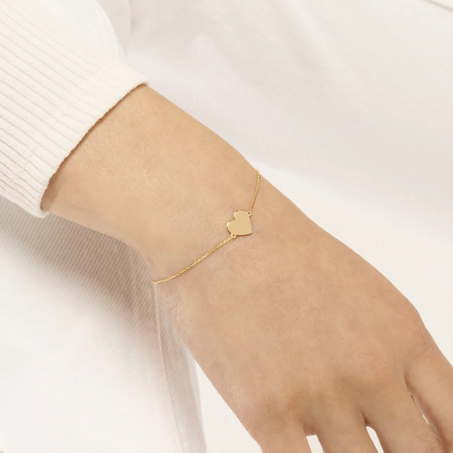 a person wearing a gold heart bracelet