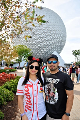 a man and woman posing for a picture in front of a large sphere