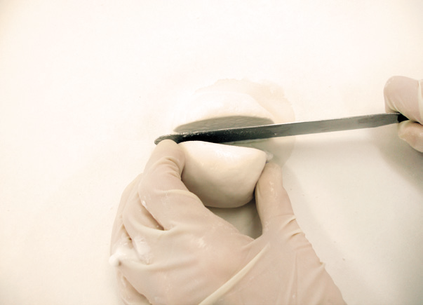 a person using a knife to cut a piece of dough