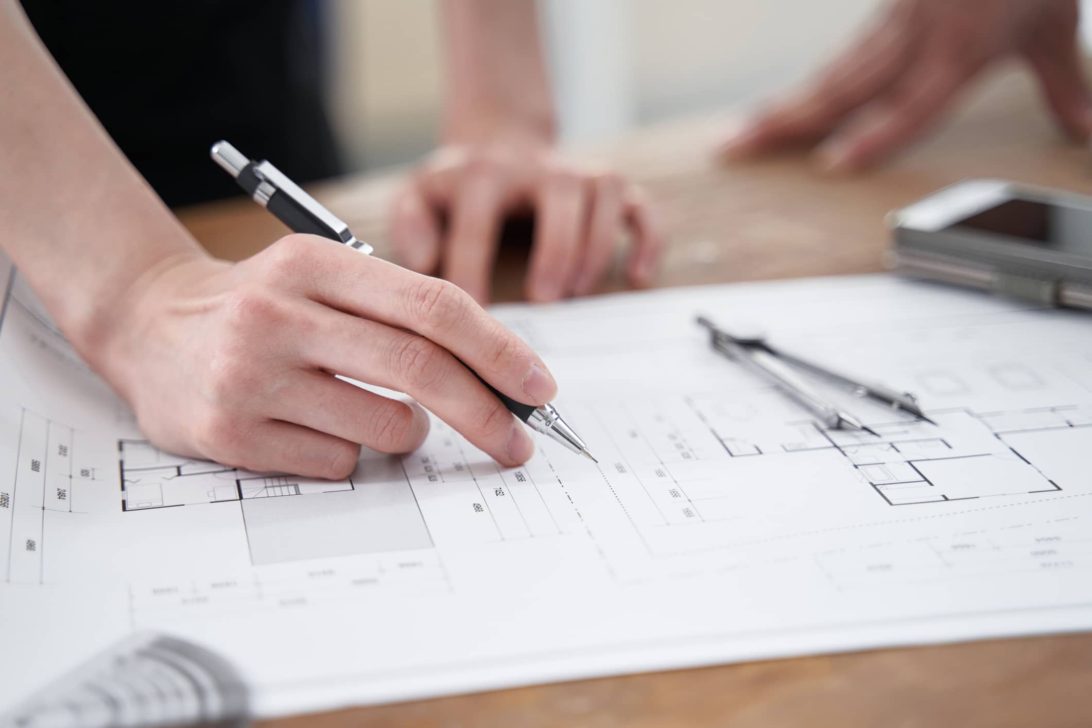 a person holding a pen over a blueprint