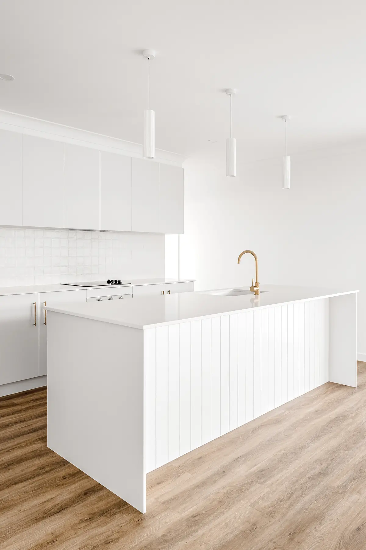 a white kitchen with a white island and wood floor