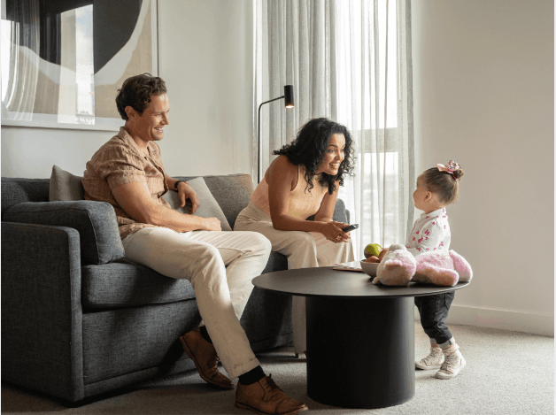 a man and woman sitting on a couch and looking at a baby