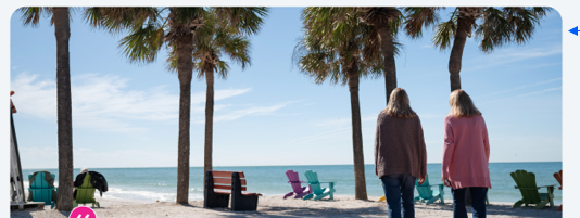 a woman standing on a beach with palm trees and chairs